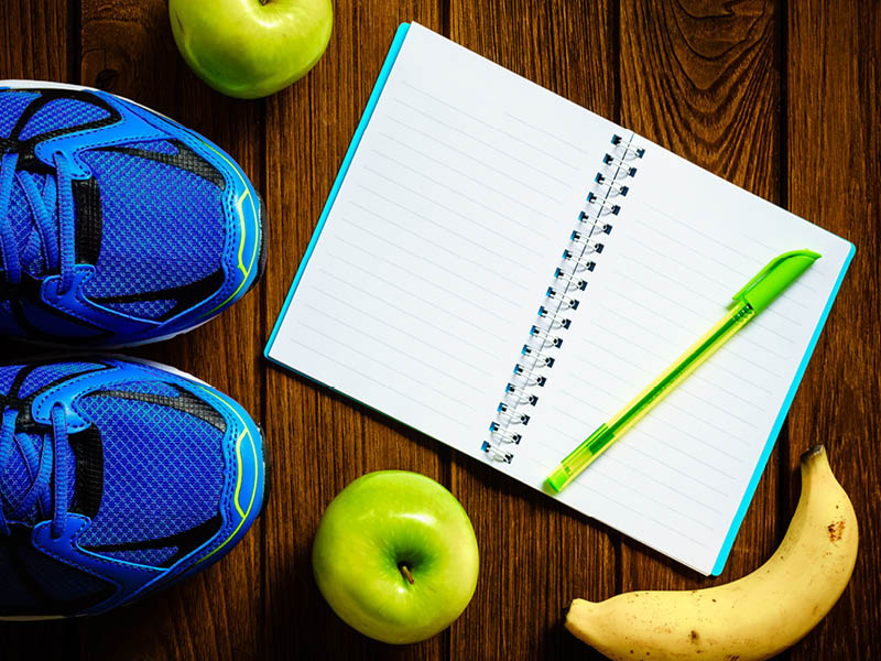 Sport shoes, apples and bananas on a wooden background. 