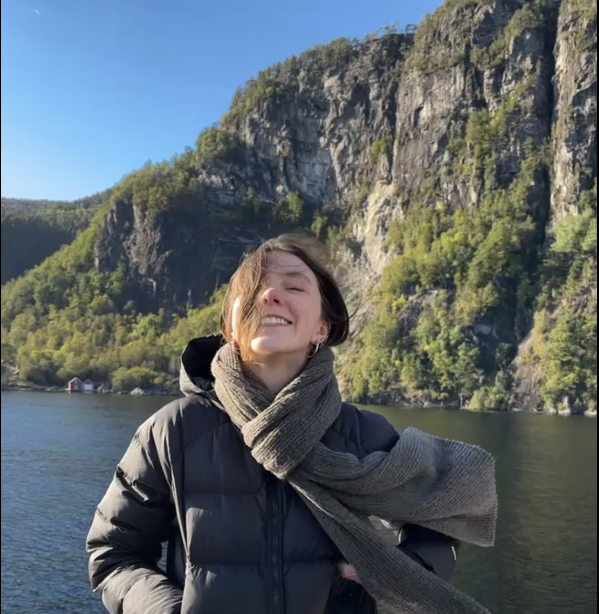 Girl smiling with cliffs and water in the background