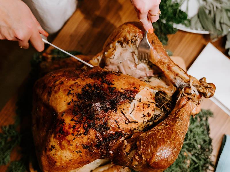 Close up of hands carving a holiday turkey.