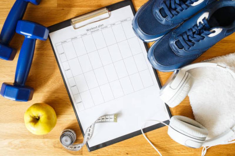 A clipboard with a rubric labeled "workout plan" next to dumbbells, an apple, measuring tape, tennis shoes, headphones, and a towel. A clipboard with a rubric labeled "workout plan" next to dumbbells, an apple, measuring tape, tennis shoes, headphones, and a towel.